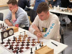 A chess tournament. A young man contemplates his next move