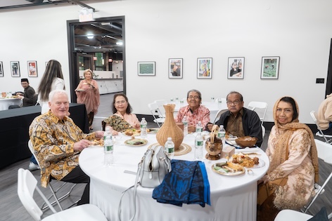 A group eating at a table smile for the camera.
