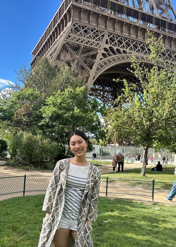 Maggie standing in front of the Eiffel Tower on a sunny day.